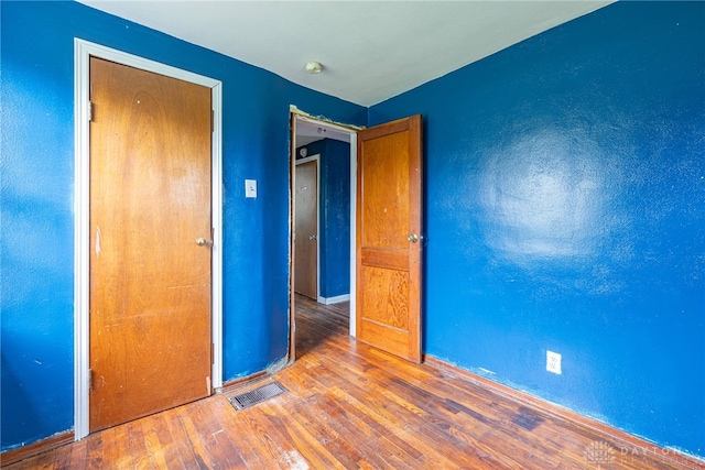 unfurnished bedroom featuring baseboards, visible vents, and hardwood / wood-style flooring