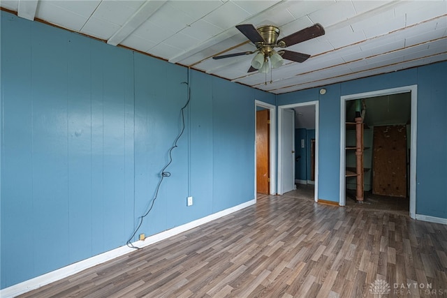 unfurnished bedroom with baseboards, a closet, wood finished floors, and a spacious closet