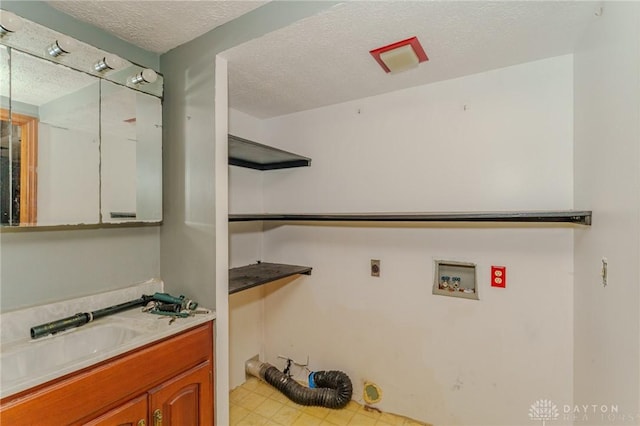 clothes washing area with a textured ceiling, tile patterned floors, electric dryer hookup, a sink, and washer hookup