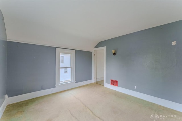 carpeted empty room with baseboards, visible vents, and lofted ceiling