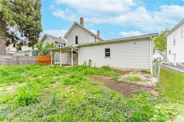 back of property with a chimney and a fenced backyard