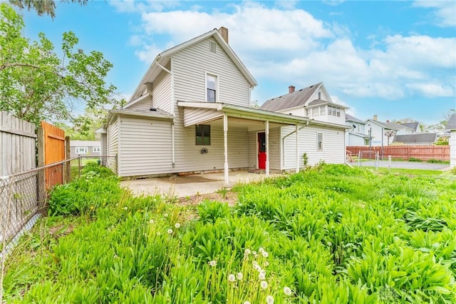 back of house featuring a chimney, a fenced backyard, and a patio area