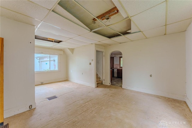 unfurnished room featuring arched walkways, baseboards, a paneled ceiling, and stairway