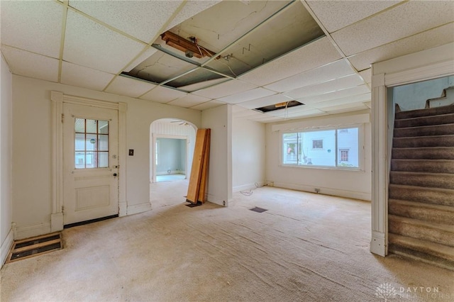 interior space featuring stairway, arched walkways, carpet flooring, and a paneled ceiling