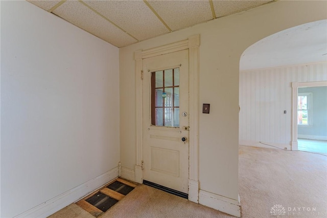entryway with arched walkways, baseboards, carpet flooring, and a drop ceiling