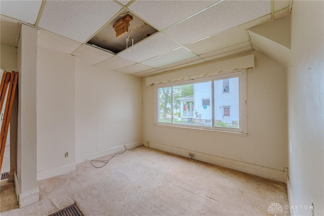carpeted spare room featuring baseboards and a drop ceiling