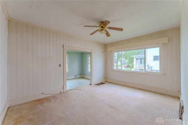 carpeted spare room featuring ceiling fan, ornamental molding, and baseboards