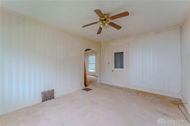 unfurnished room featuring carpet floors, arched walkways, a ceiling fan, and visible vents