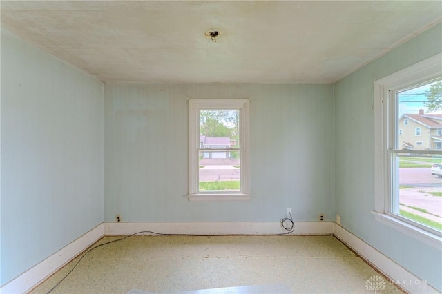 spare room featuring a healthy amount of sunlight and baseboards