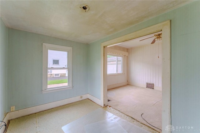 empty room featuring baseboards, ceiling fan, and visible vents