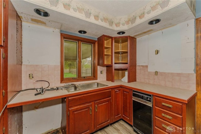 kitchen with a sink, light countertops, light wood finished floors, and tasteful backsplash