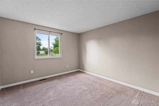 carpeted empty room with visible vents, a textured ceiling, and baseboards