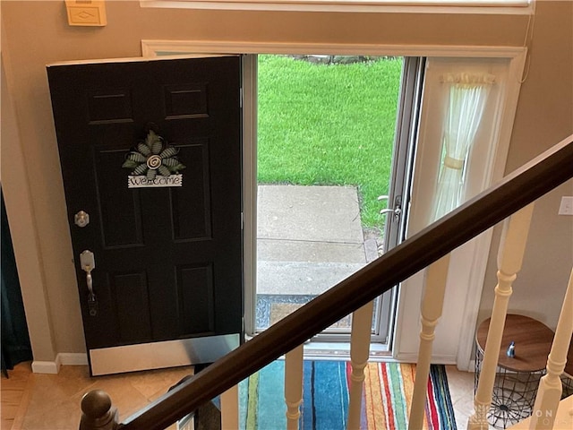 foyer with baseboards, light tile patterned floors, and stairway