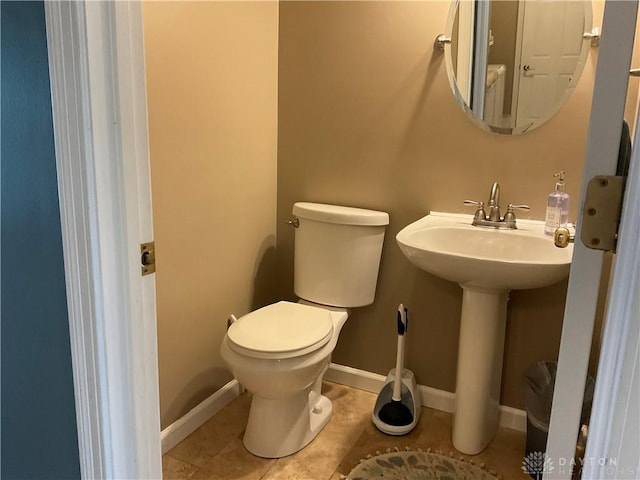 half bathroom featuring a sink, baseboards, tile patterned flooring, and toilet
