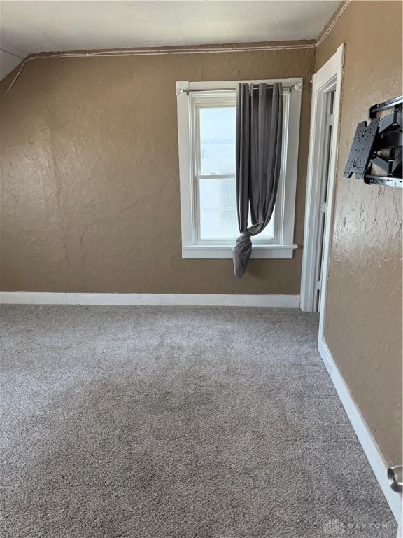 1080 Linden Ave, Dayton, OH 45410 - carpeted spare room featuring baseboards, a textured wall, ornamental molding, and vaulted ceiling