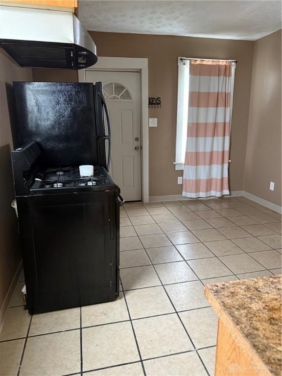 1080 Linden Ave, Dayton, OH 45410 - kitchen featuring black appliances, range hood, light tile patterned flooring, and baseboards