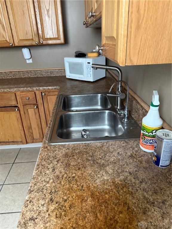 1080 Linden Ave, Dayton, OH 45410 - kitchen with white microwave, a sink, dark countertops, and light tile patterned floors