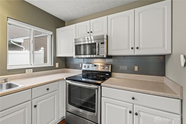 2750 Twin Lakes Dr, Troy, OH 45373 - kitchen with appliances with stainless steel finishes, white cabinetry, backsplash, and a textured ceiling
