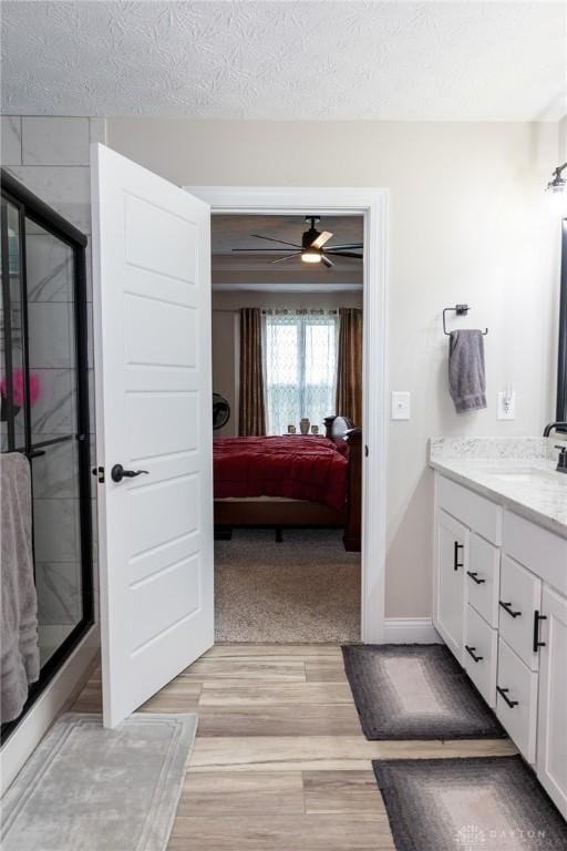 ensuite bathroom featuring vanity, wood finished floors, ensuite bathroom, and a stall shower