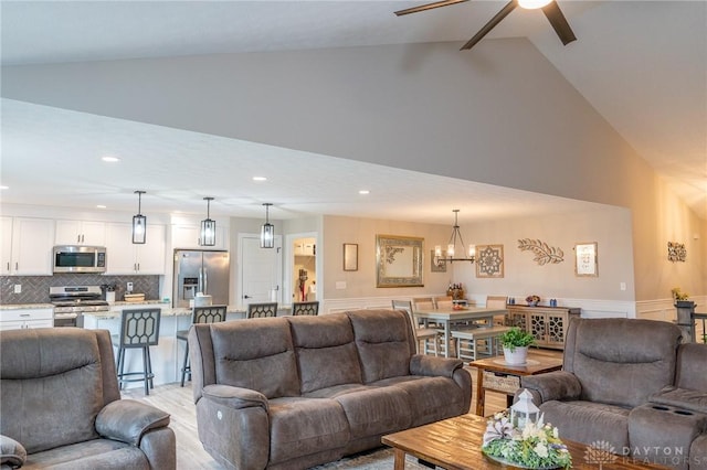 living area featuring recessed lighting, light wood-style floors, ceiling fan with notable chandelier, and high vaulted ceiling