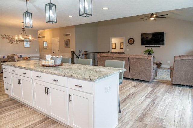 kitchen with open floor plan, visible vents, ceiling fan with notable chandelier, and light wood-style floors