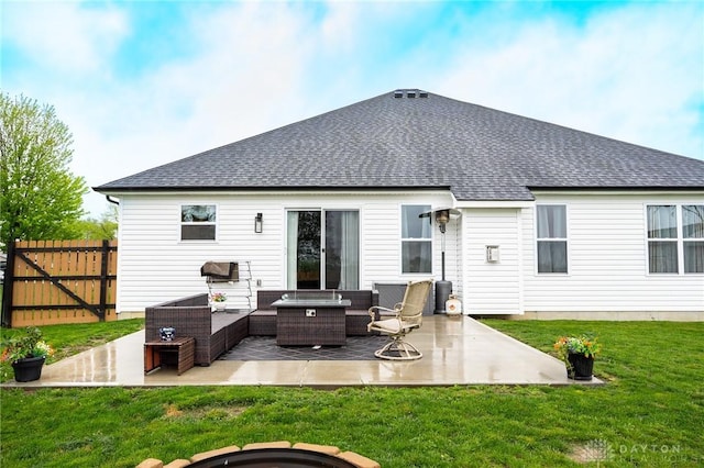 rear view of house with a lawn, an outdoor living space with a fire pit, a patio area, and roof with shingles