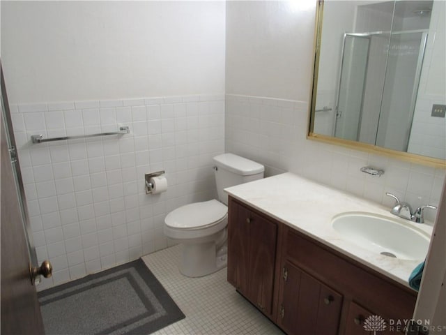 bathroom featuring wainscoting, a shower with shower door, vanity, toilet, and tile walls