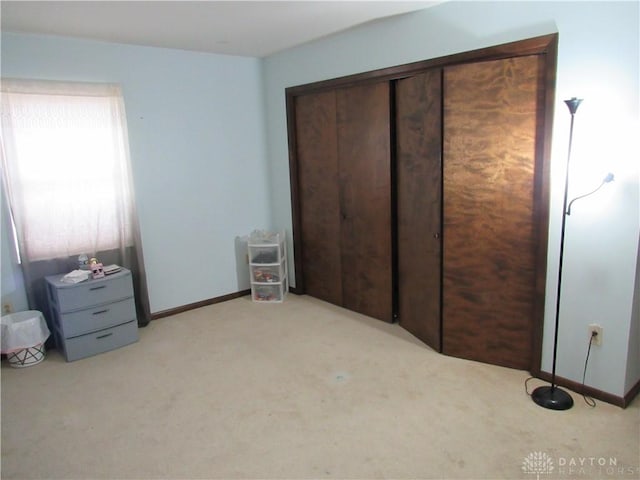 unfurnished bedroom with a closet, baseboards, and light carpet