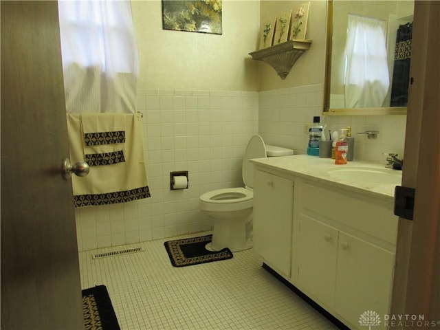 bathroom with visible vents, tile walls, tile patterned floors, vanity, and toilet
