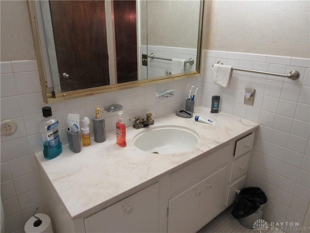 bathroom featuring tile walls, wainscoting, and vanity