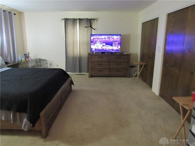 bedroom with light carpet and two closets