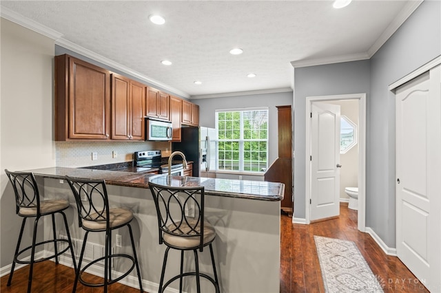 4266 Straight Arrow Rd, Beavercreek, OH 45430 - kitchen with crown molding, brown cabinetry, a peninsula, and stainless steel appliances