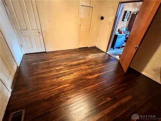 unfurnished bedroom with dark wood-style floors and visible vents