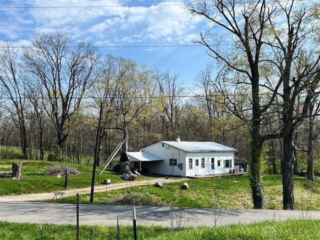 view of front of home with a front lawn and a forest view