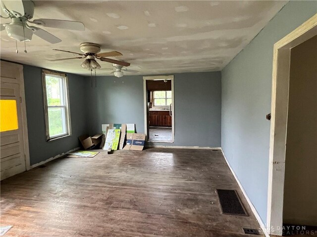 unfurnished room featuring a ceiling fan, a healthy amount of sunlight, visible vents, and wood finished floors