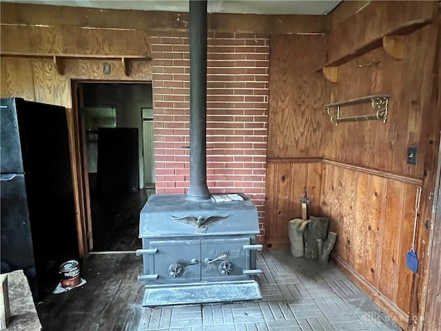 room details featuring a wood stove, wood walls, and freestanding refrigerator