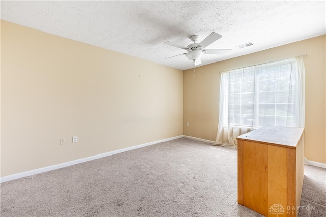 unfurnished room featuring a ceiling fan, a textured ceiling, visible vents, baseboards, and light carpet