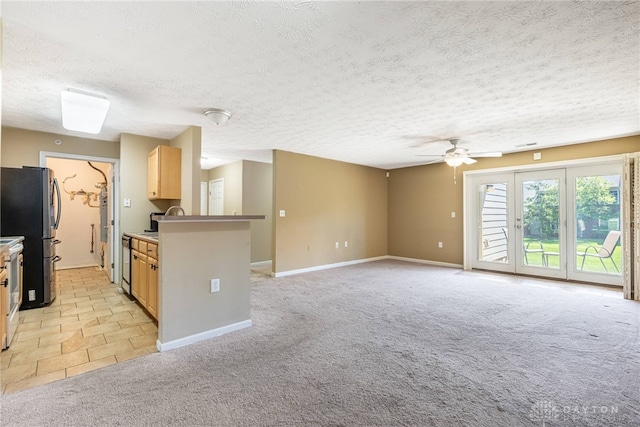 kitchen featuring light colored carpet, a textured ceiling, baseboards, and ceiling fan