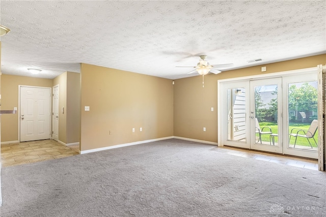 carpeted empty room with a textured ceiling, visible vents, ceiling fan, tile patterned flooring, and baseboards