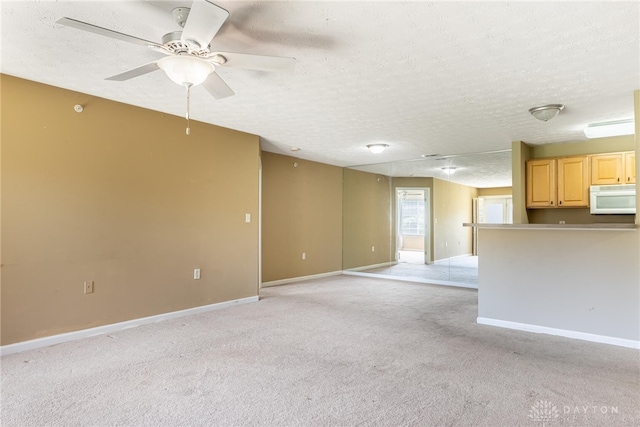 unfurnished living room with light carpet, a textured ceiling, baseboards, and ceiling fan