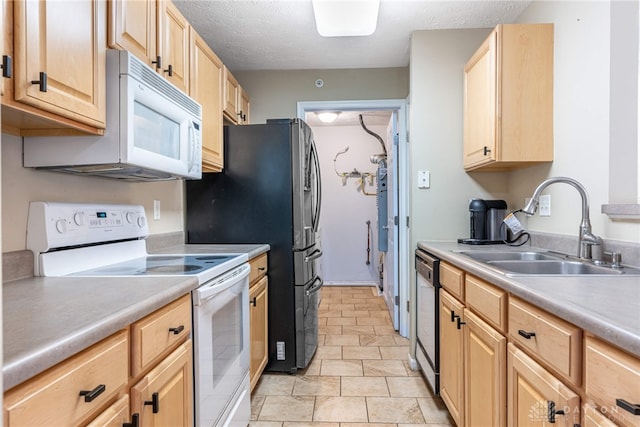 kitchen with light brown cabinetry, a textured ceiling, white appliances, a sink, and light countertops