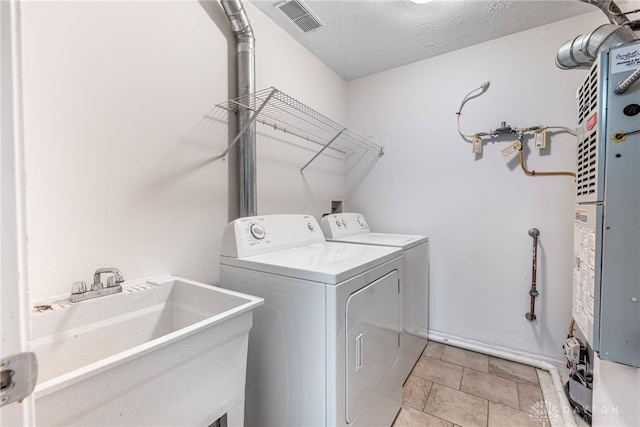 washroom with independent washer and dryer, a textured ceiling, visible vents, a sink, and laundry area