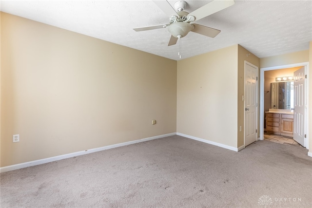 unfurnished bedroom featuring connected bathroom, light carpet, baseboards, and ceiling fan