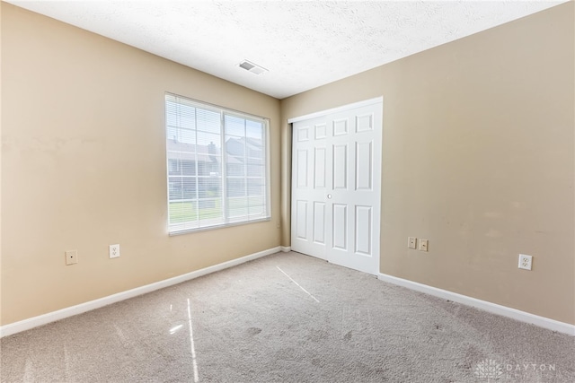 unfurnished bedroom with a closet, visible vents, baseboards, and carpet floors