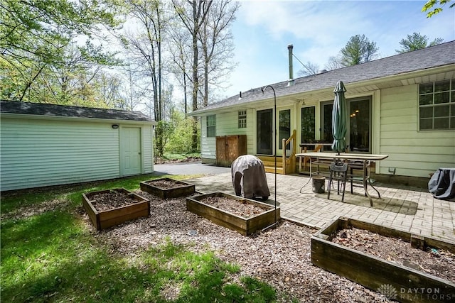 rear view of house featuring an outdoor structure, a patio, and a vegetable garden