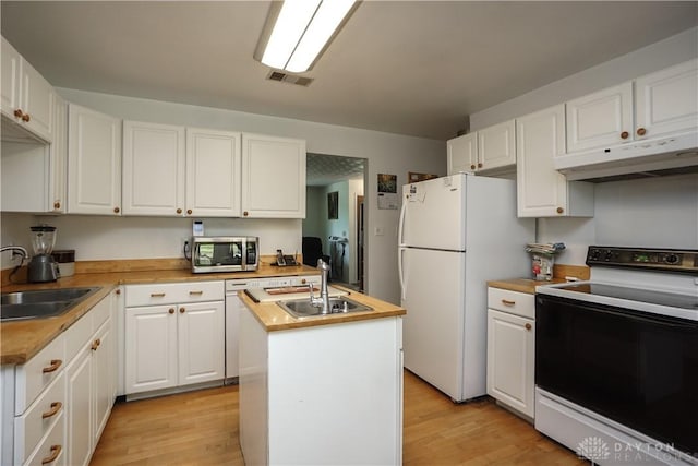kitchen with a sink, white appliances, under cabinet range hood, and visible vents