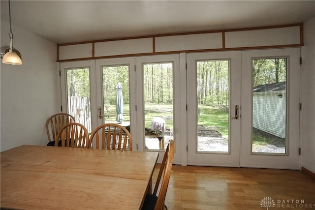 dining space with light wood finished floors and french doors