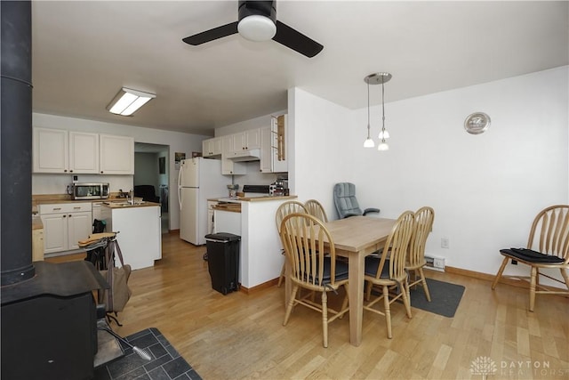dining area featuring ceiling fan, baseboards, and light wood-type flooring
