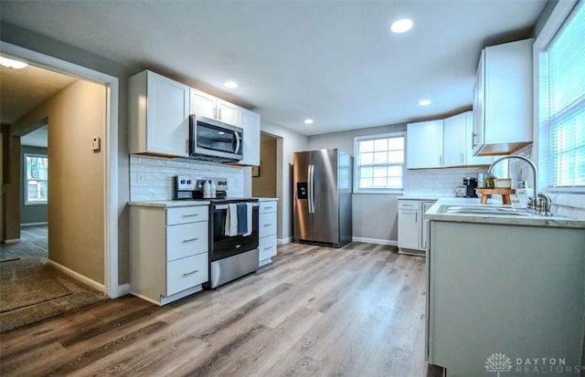 2004 N Reardon Dr, Dayton, OH 45420 - kitchen featuring light wood finished floors, a sink, white cabinetry, light countertops, and appliances with stainless steel finishes
