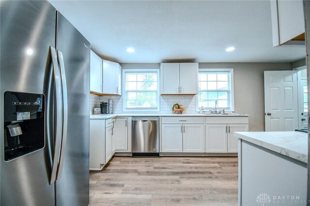 2004 N Reardon Dr, Dayton, OH 45420 - kitchen with tasteful backsplash, light wood finished floors, light countertops, white cabinets, and appliances with stainless steel finishes